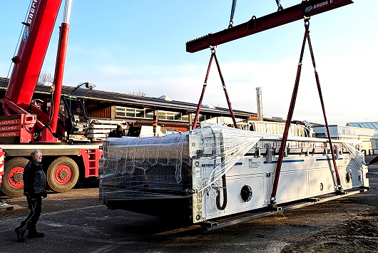 Kran hebt Laminator von Transporter