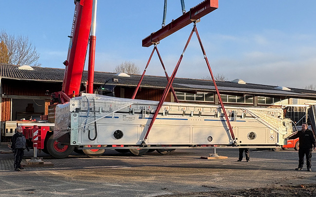 Kran hebt Laminator von Transporter